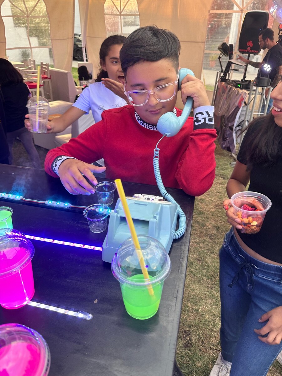 Teléfono azul de CoolpartyRinng colocado en mesa de evento con bebidas humeantes